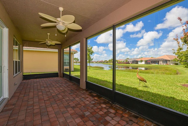 unfurnished sunroom featuring a water view and ceiling fan