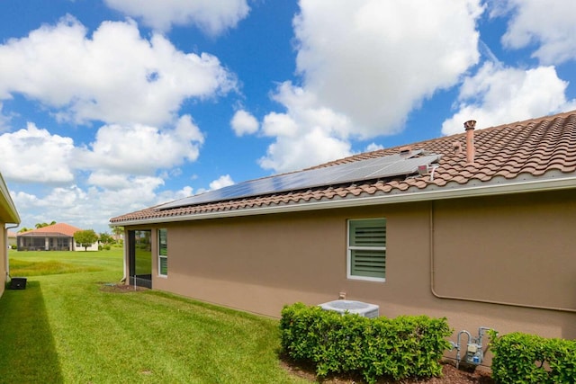 view of home's exterior featuring solar panels, a yard, and central AC