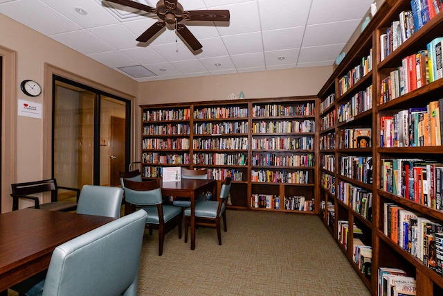 interior space featuring carpet floors, bookshelves, and ceiling fan