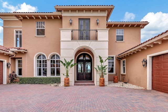 view of exterior entry featuring french doors and a balcony