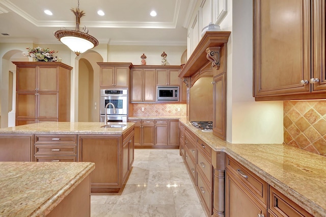 kitchen featuring stainless steel appliances, a center island, light stone counters, hanging light fixtures, and tasteful backsplash