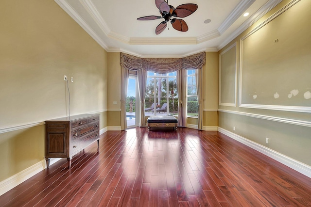 unfurnished room featuring ceiling fan, dark hardwood / wood-style floors, a tray ceiling, and ornamental molding