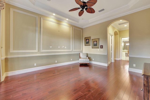 unfurnished room with hardwood / wood-style floors, ceiling fan, a raised ceiling, and ornamental molding