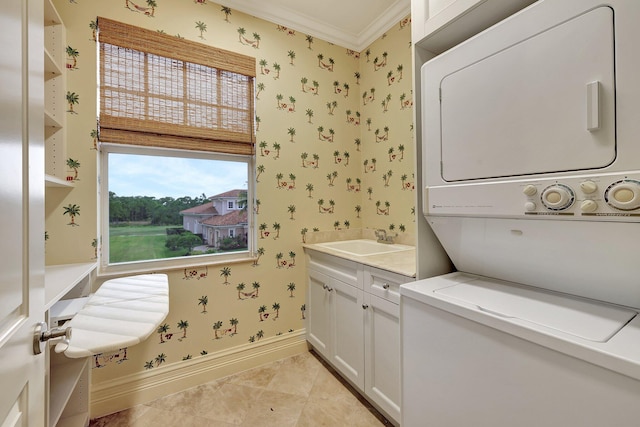 clothes washing area featuring cabinets, crown molding, stacked washer / dryer, and sink