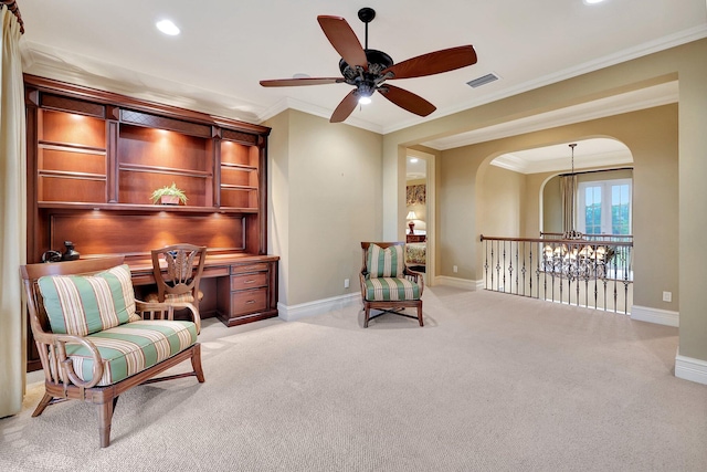 sitting room with built in desk, light colored carpet, ceiling fan with notable chandelier, and crown molding