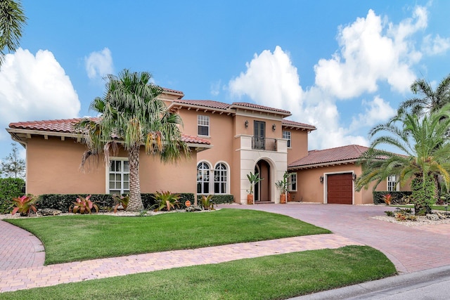 mediterranean / spanish home featuring a garage, a front lawn, and a balcony