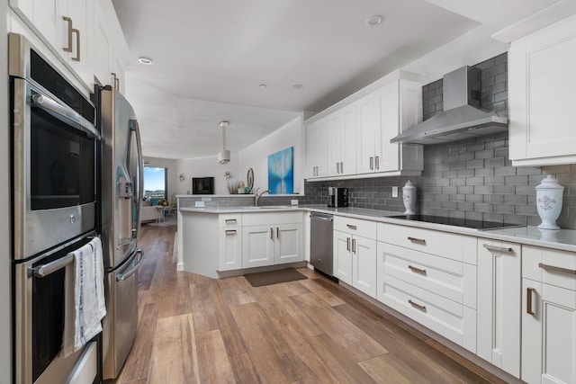 kitchen featuring sink, tasteful backsplash, white cabinets, kitchen peninsula, and wall chimney exhaust hood