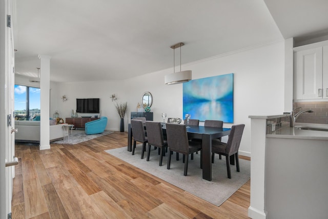 dining space featuring crown molding, sink, and light hardwood / wood-style flooring