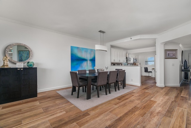 dining room with ornamental molding and light hardwood / wood-style floors