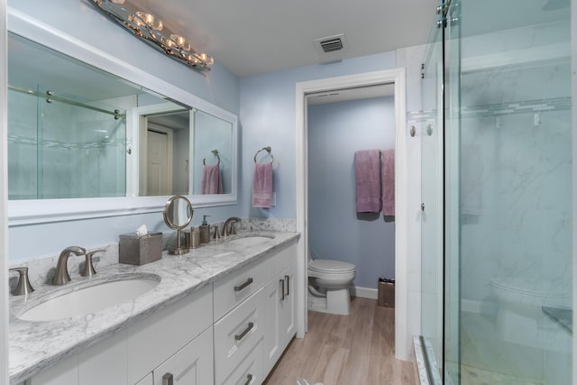 bathroom featuring a shower with door, wood-type flooring, vanity, and toilet