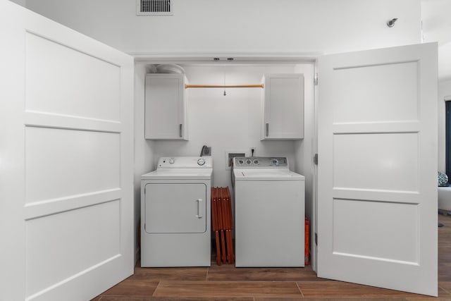 laundry area featuring cabinets, washing machine and dryer, and dark hardwood / wood-style floors