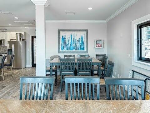 dining area featuring crown molding, light hardwood / wood-style floors, and ornate columns