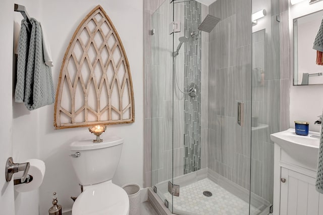 bathroom featuring toilet, a shower with shower door, and vanity