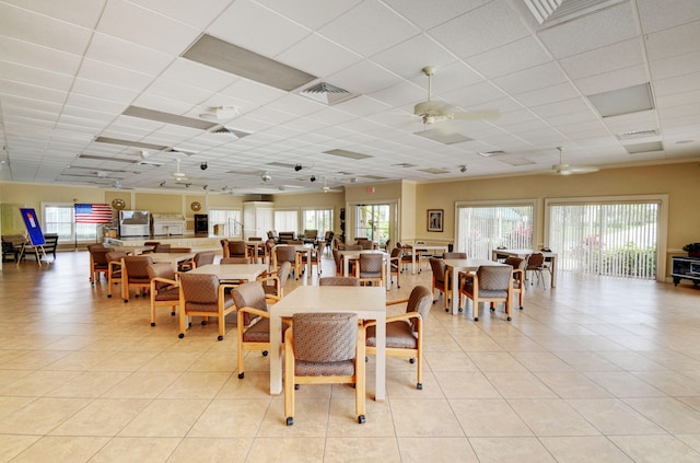 tiled dining room with ceiling fan, a paneled ceiling, and plenty of natural light