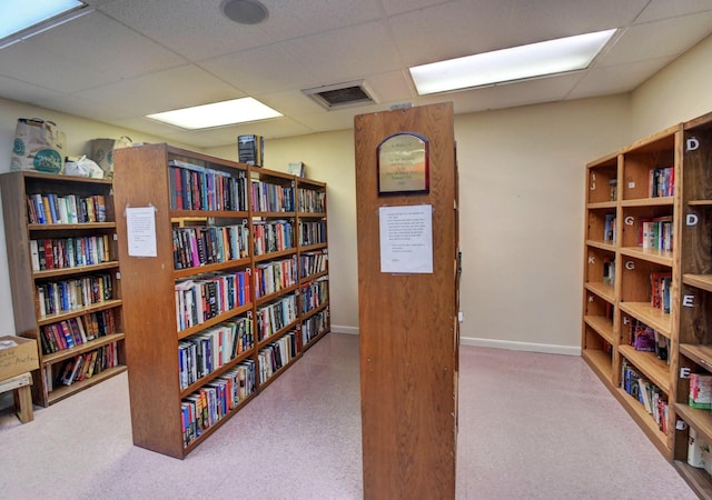 interior space with a drop ceiling and light colored carpet