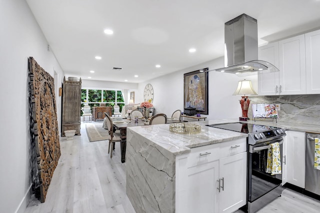 kitchen featuring light stone countertops, light wood-type flooring, island exhaust hood, electric stove, and white cabinets