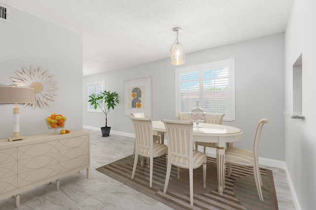 dining area with light wood-type flooring and a textured ceiling