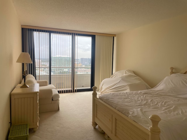 bedroom with expansive windows, access to exterior, carpet floors, and a textured ceiling