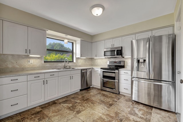 kitchen with decorative backsplash, sink, stainless steel appliances, and white cabinets