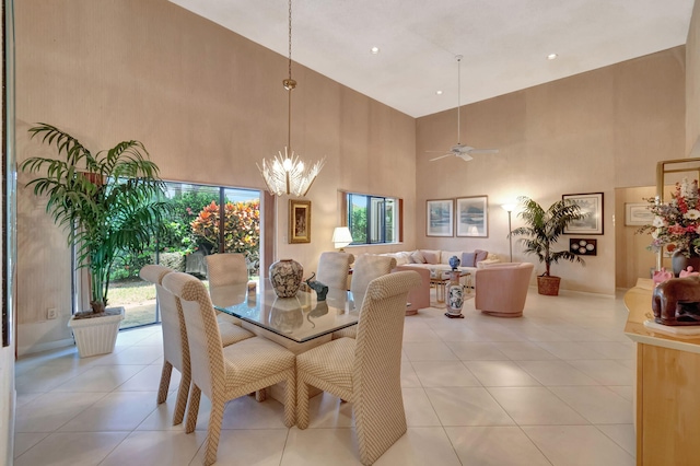 tiled dining space featuring a towering ceiling and ceiling fan with notable chandelier