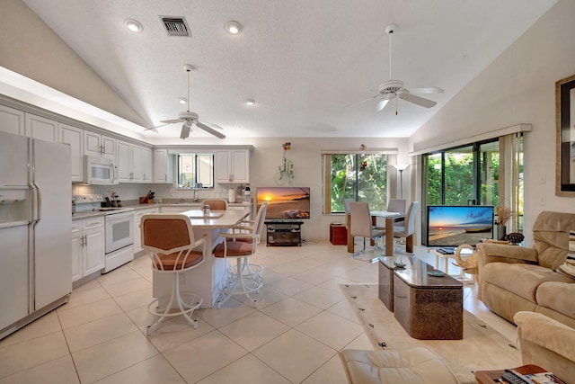 kitchen featuring white cabinetry, white appliances, a center island, and vaulted ceiling