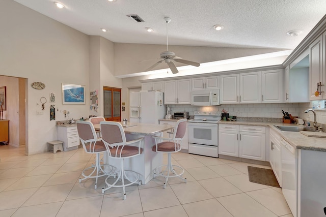 kitchen with sink, tasteful backsplash, a center island, white appliances, and white cabinets