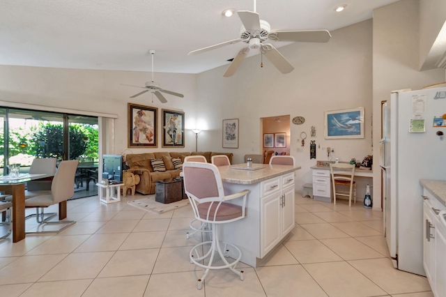 kitchen featuring light tile patterned flooring, a center island, white cabinets, and white refrigerator