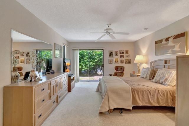 bedroom featuring ceiling fan, access to exterior, light carpet, and a textured ceiling