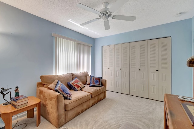 living room featuring ceiling fan, light colored carpet, and a textured ceiling