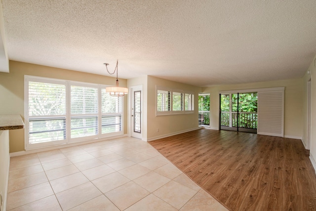 spare room with a textured ceiling, light hardwood / wood-style flooring, and plenty of natural light