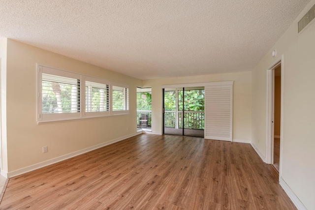 unfurnished room featuring light wood-type flooring and a textured ceiling