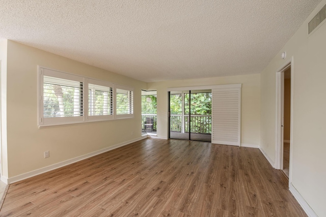 unfurnished room with hardwood / wood-style flooring and a textured ceiling