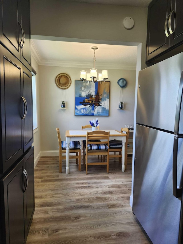 dining space with ornamental molding, wood-type flooring, and an inviting chandelier