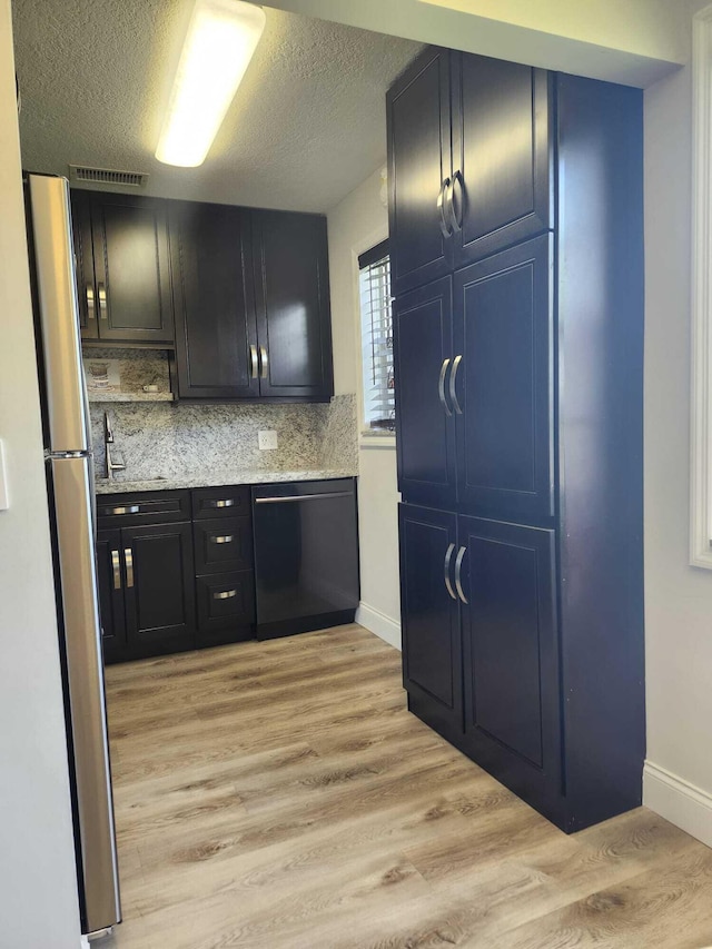 kitchen featuring stainless steel refrigerator, dishwasher, backsplash, a textured ceiling, and light wood-type flooring