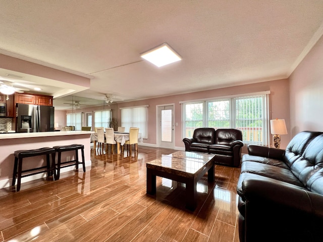 living room featuring wood-type flooring, a textured ceiling, and ceiling fan