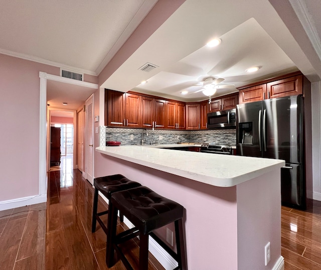 kitchen featuring appliances with stainless steel finishes, decorative backsplash, crown molding, dark wood-type flooring, and ceiling fan