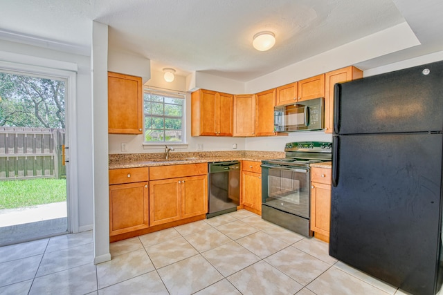 kitchen featuring black appliances, a wealth of natural light, and light tile patterned floors