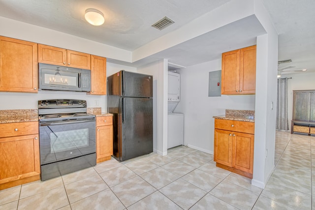 kitchen with light tile patterned floors, black appliances, electric panel, and stacked washer / drying machine