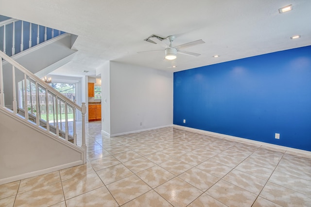 spare room featuring light tile patterned flooring and ceiling fan with notable chandelier