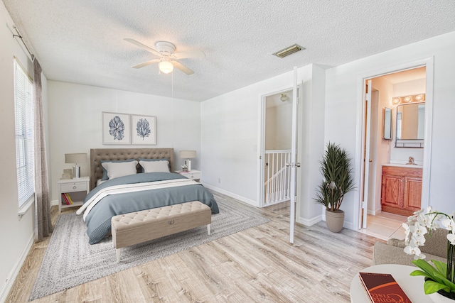 bedroom featuring multiple windows, ensuite bathroom, light hardwood / wood-style flooring, and ceiling fan