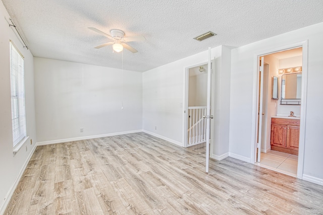 unfurnished room with a textured ceiling, ceiling fan, and light wood-type flooring