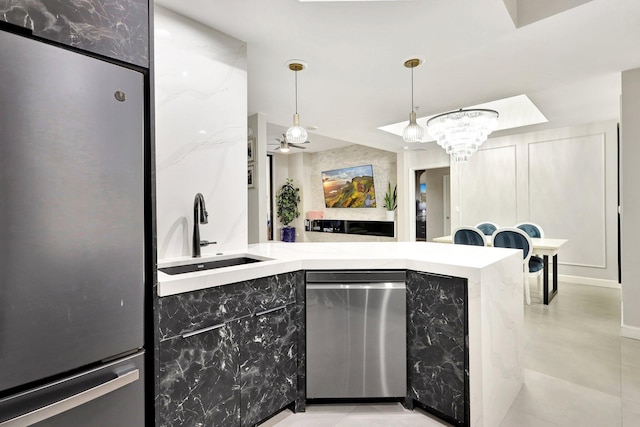 kitchen featuring decorative light fixtures, sink, appliances with stainless steel finishes, beverage cooler, and ceiling fan with notable chandelier