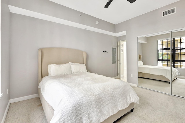 bedroom with light carpet, electric panel, ceiling fan, and a closet