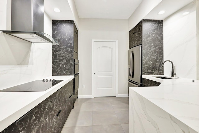 kitchen featuring stainless steel refrigerator, light stone countertops, wall chimney exhaust hood, and black electric stovetop