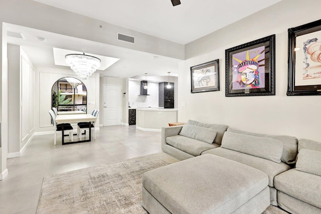 tiled living room featuring ceiling fan with notable chandelier