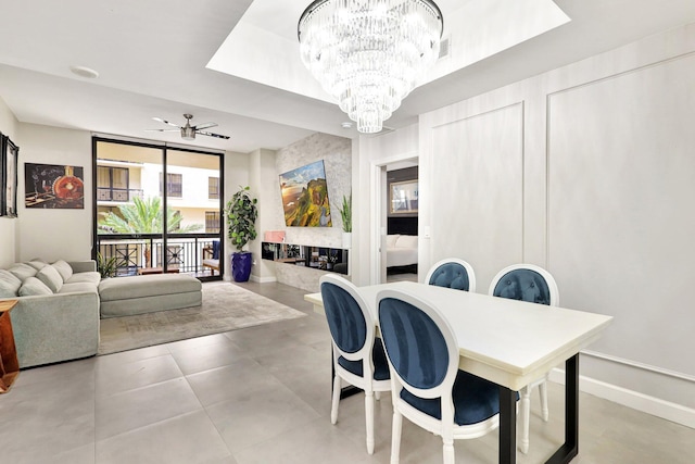 dining room with floor to ceiling windows, a raised ceiling, and ceiling fan with notable chandelier