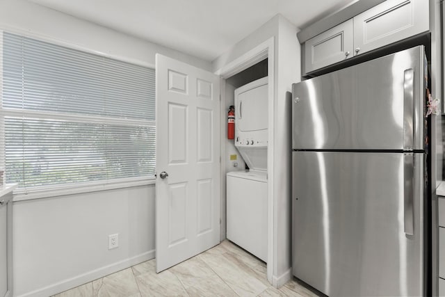 kitchen with light tile patterned flooring, stacked washer / dryer, and stainless steel refrigerator