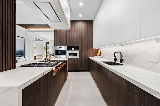 kitchen featuring light stone counters, white cabinets, sink, appliances with stainless steel finishes, and decorative backsplash