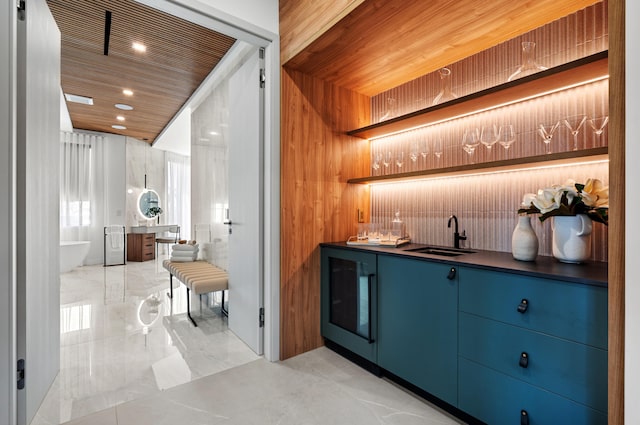 bar with blue cabinetry, wooden walls, sink, and wooden ceiling