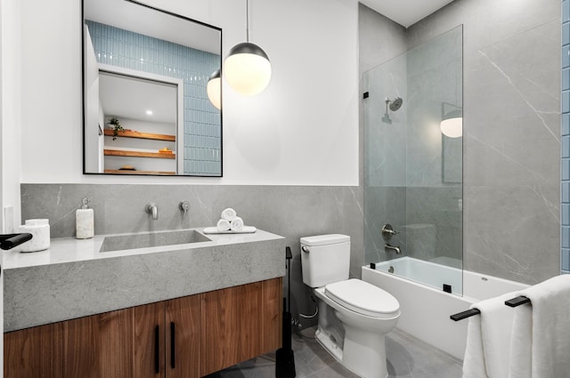 full bathroom with vanity, tile walls, tiled shower / bath combo, and toilet